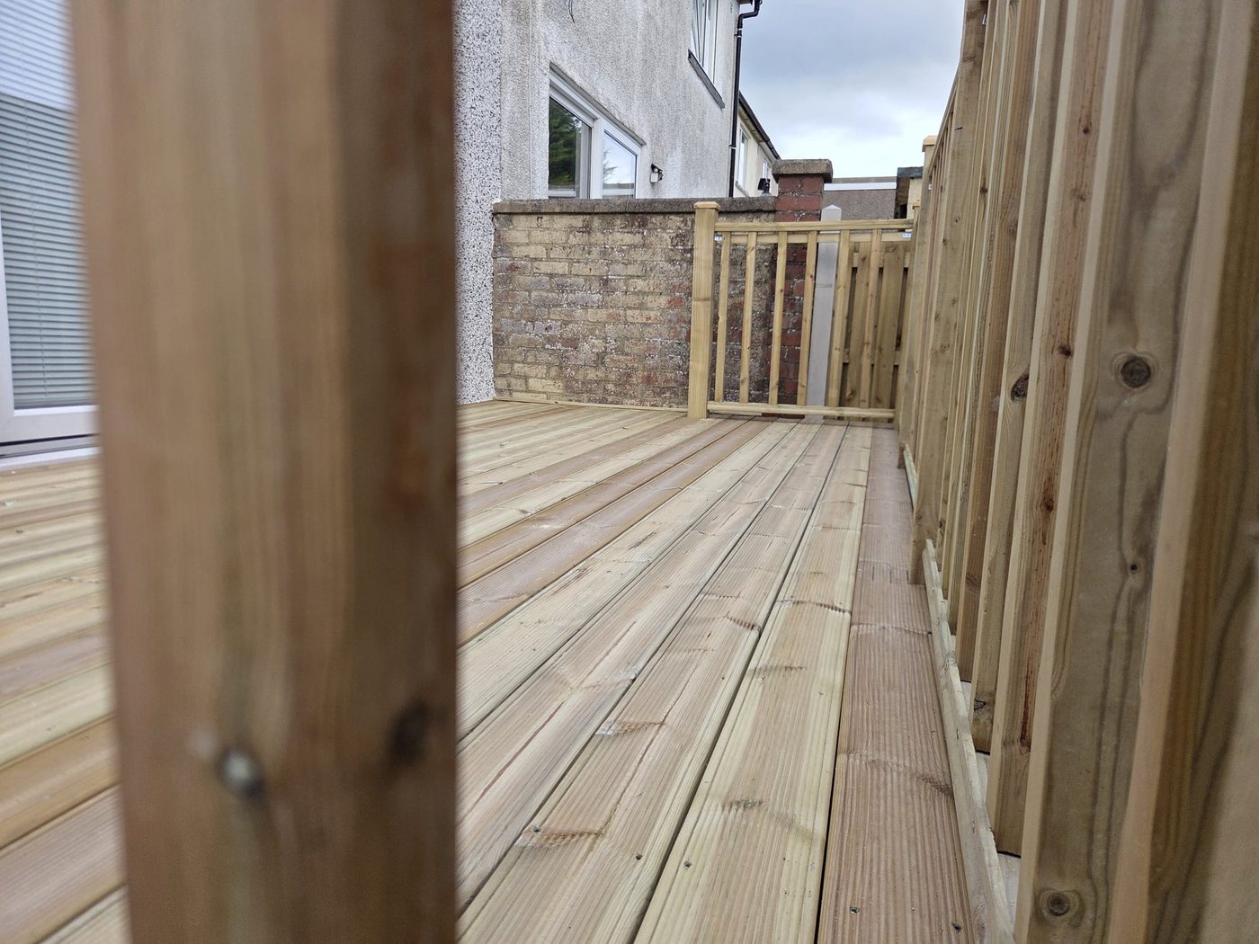 Grooved deck boards running the length of a new deck beside patio doors