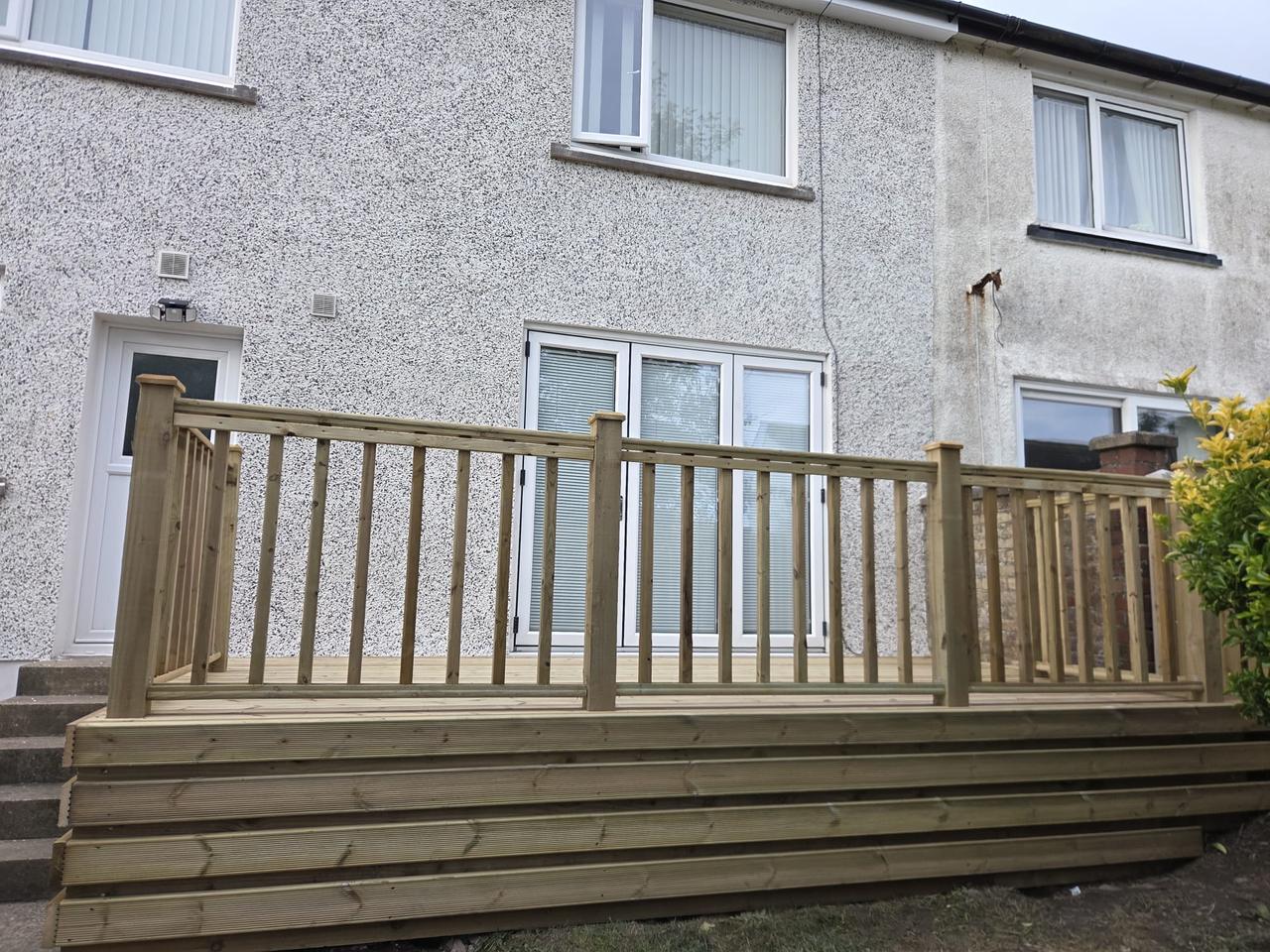 Raised timber deck with a spindle balustrade across the back of a house