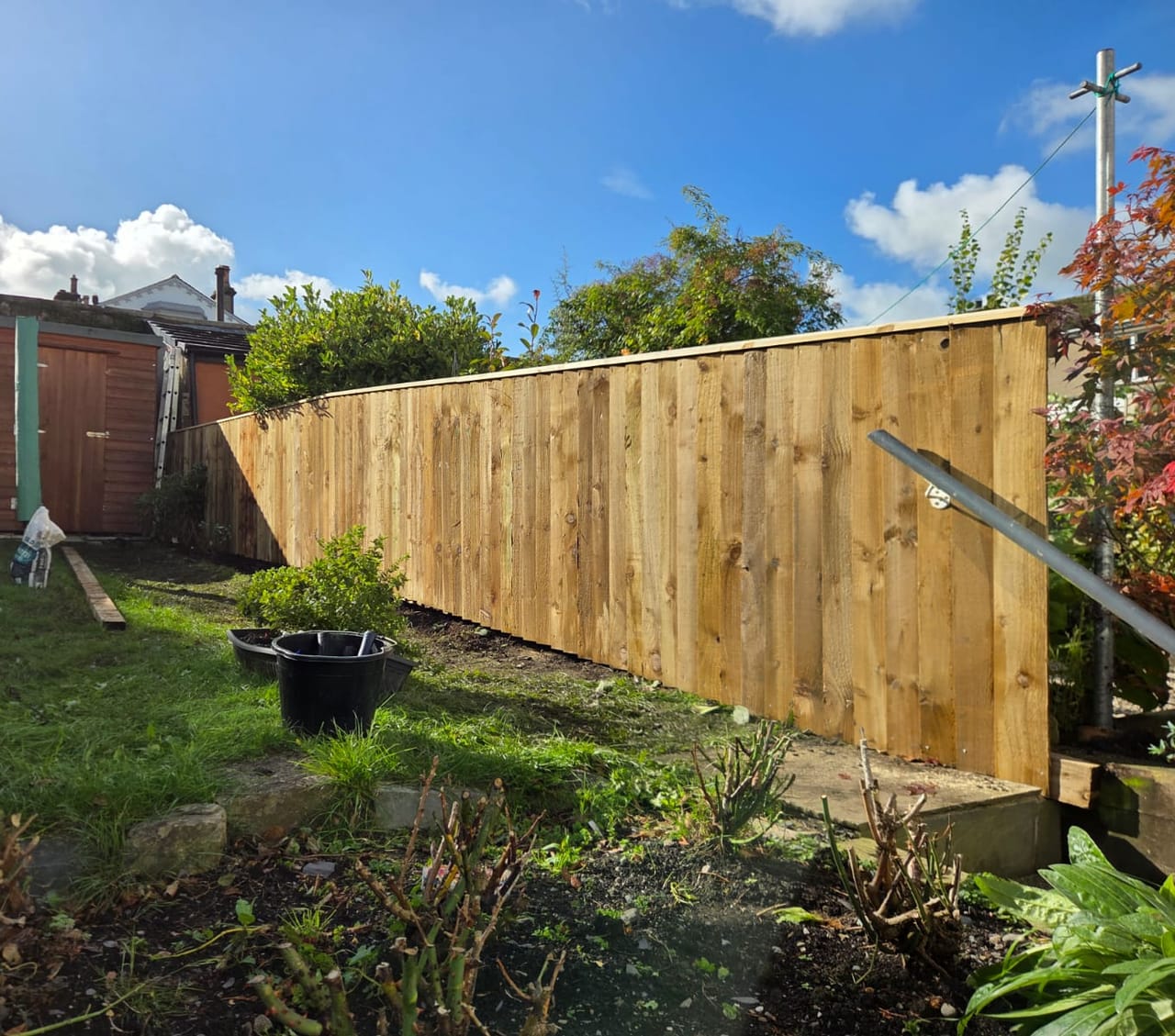 New featheredge fence with a capping rail running the length of a sloping back garden